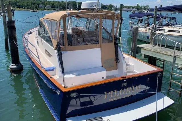 Slide: The Image of 2001 Legacy Yachts Express boat docked in a marina, featuring a tan canopy and blue hull. - 103