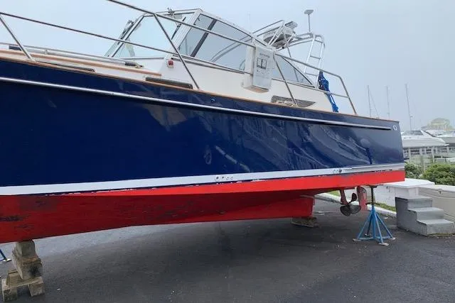 Slide: The Image of 2001 Legacy Yachts Express boat with blue and red hull on dry dock. - 105
