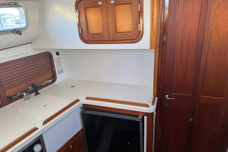 Slide: The Image of 2001 Legacy Soft Top boat interior with wooden cabinets and compact kitchen area. - 32