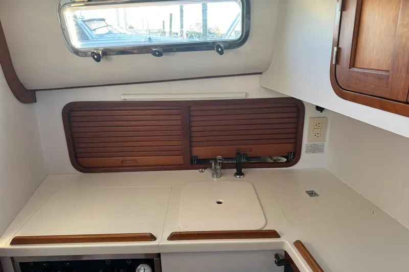 Slide: The Image of 2001 Legacy Soft Top boat interior with wooden cabinets and compact sink area. - 33