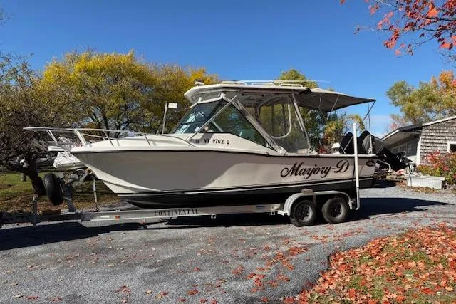 The Image of 2001 Dusky 252 CSS boat on trailer, surrounded by autumn foliage. - 1