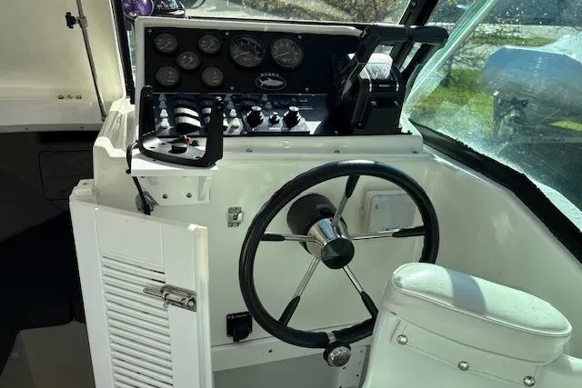 Slide: The Image of 2001 Dusky 252 CSS boat cockpit with steering wheel and control panel. - 10