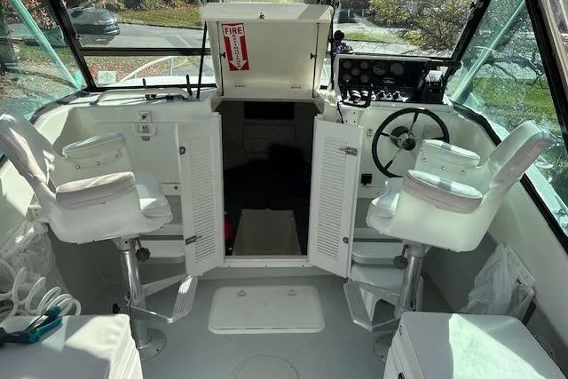Slide: The Image of 2001 Dusky 252 CSS boat interior with helm, seating, and storage compartments. - 8