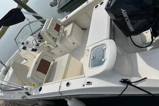 Slide: The Image of 2023 Cobia 220 DC boat with Mercury engine, docked, featuring spacious seating and modern design. - 2