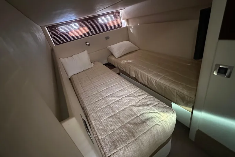 Slide: The Image of Twin beds in the 2011 Sea Ray 470 Sundancer cabin, featuring cozy bedding and ambient lighting. - 10