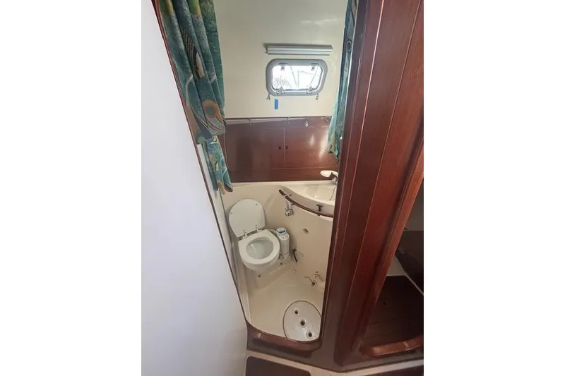 Slide: The Image of Bathroom interior of 1997 Beneteau Oceanis 321 sailboat, featuring toilet and porthole window. - 22