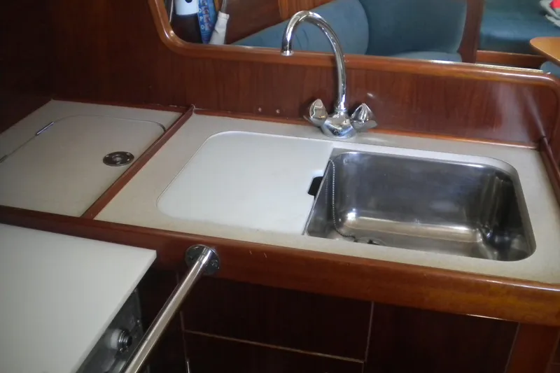 Slide: The Image of Galley sink area in 1997 Beneteau Oceanis 321 sailboat, featuring wood finish and stainless steel sink. - 33