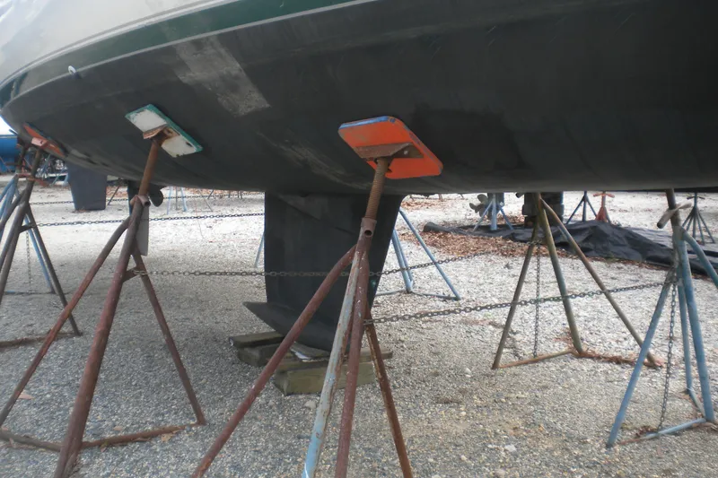 Slide: The Image of 1997 Beneteau Oceanis 321 sailboat on stands, showing hull and keel in a boatyard. - 44