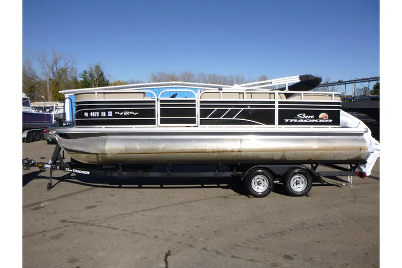The Image of 2022 Sun Tracker Party Barge 22 DLX pontoon boat on trailer, parked outdoors. - 1
