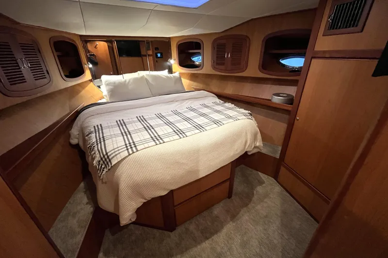 Slide: The Image of Cozy cabin interior of 2010 Mikelson 43 Sportfisher with bed and wooden accents. - 11