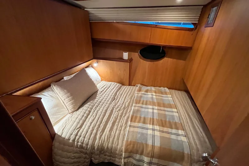 Slide: The Image of Cozy cabin interior of 2010 Mikelson 43 Sportfisher with wood paneling and comfortable bedding. - 17
