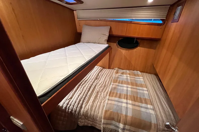 Slide: The Image of Cozy cabin interior of 2010 Mikelson 43 Sportfisher with wooden paneling and twin beds. - 18