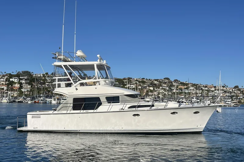 Slide: The Image of 2010 Mikelson 43 Sportfisher yacht cruising in a scenic harbor setting. - 56