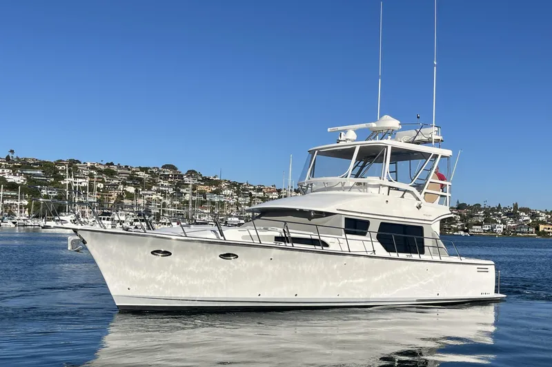 Slide: The Image of 2010 Mikelson 43 Sportfisher yacht on calm water, with coastal backdrop. - 58