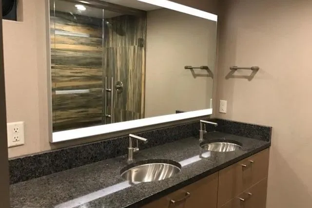 Slide: The Image of Modern bathroom with double sinks, granite countertop, large mirror, and glass shower. Adonia 7518, 2017. - 3