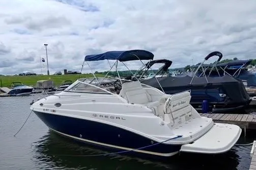 Slide: The Image of 2005 Regal Commodore 265 boat docked at marina under cloudy sky. - 2
