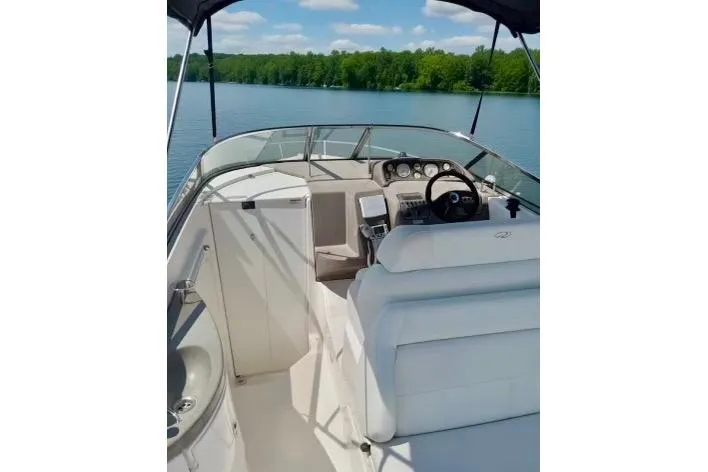 Slide: The Image of 2005 Regal Commodore 265 boat interior with steering wheel, dashboard, and seating on a calm lake. - 3