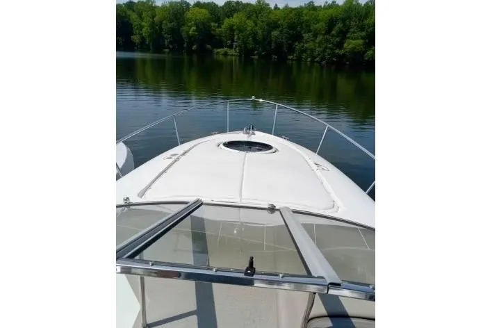 Slide: The Image of 2005 Regal Commodore 265 boat on calm lake with lush green shoreline. - 5