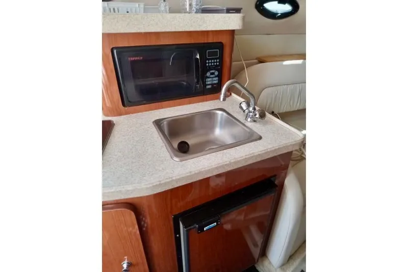Slide: The Image of Compact kitchen area in a 2005 Regal Commodore 265 boat with sink and microwave. - 9