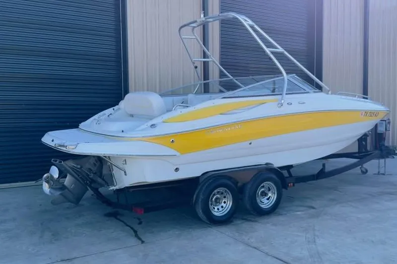 Slide: The Image of 2005 Crownline 220 EX boat on trailer, yellow and white, parked outside a garage. - 3