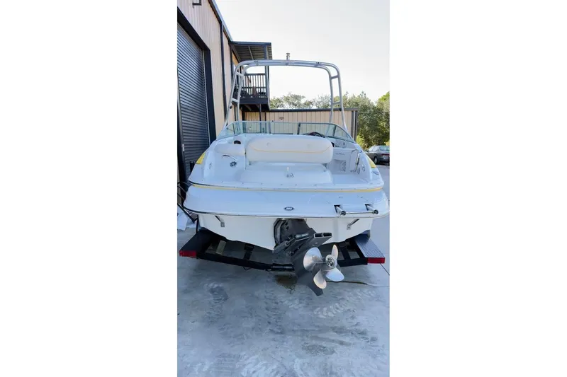 Slide: The Image of 2005 Crownline 220 EX boat on trailer, rear view, parked near a building. - 4