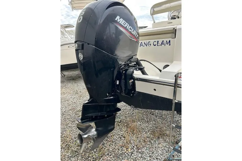 Slide: The Image of 2023 Cobia 220DC boat with Mercury outboard motor on gravel surface. - 2