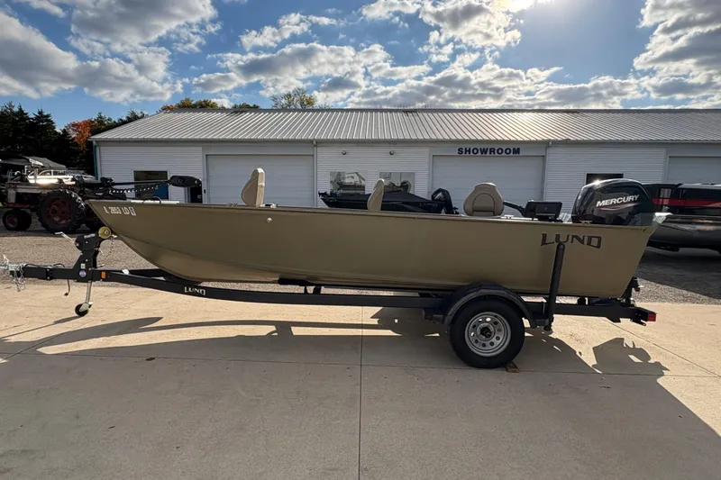 Slide: The Image of 2022 Lund 1800 Alaskan Tiller boat on trailer outside showroom under cloudy sky. - 4
