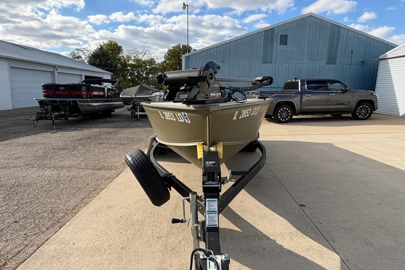 Slide: The Image of 2022 Lund 1800 Alaskan Tiller boat on trailer, parked near trucks and buildings. - 6