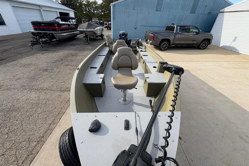 Slide: The Image of 2022 Lund 1800 Alaskan Tiller boat with seating, parked near a truck and other boats. - 8