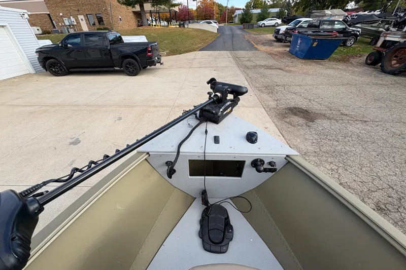 Slide: The Image of 2022 Lund 1800 Alaskan Tiller boat with trolling motor, parked near vehicles. - 9