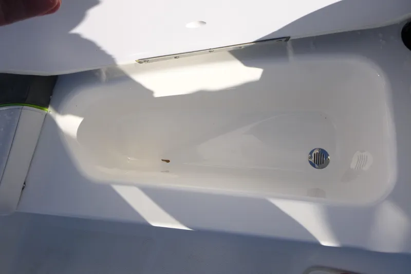 Slide: The Image of 2024 Tahoe T16 boat storage compartment with drain plug, partially shaded. - 9