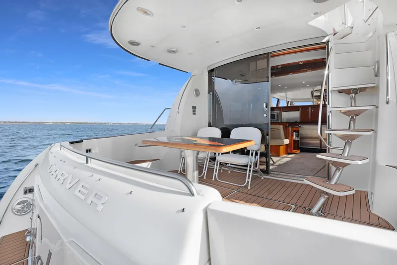 Slide: The Image of 2005 Carver 560 Voyager yacht deck with seating, table, and stairs, overlooking the ocean. - 37