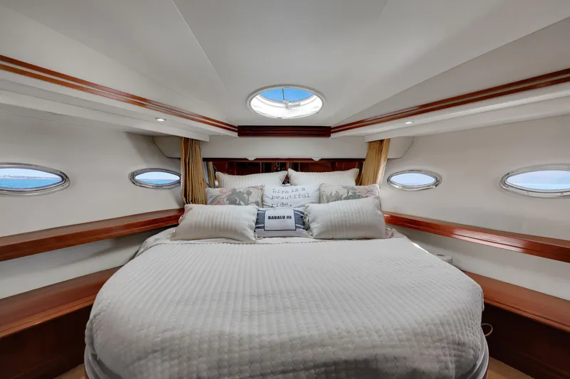 Slide: The Image of Luxurious 2005 Carver 560 Voyager yacht bedroom with elegant bedding and porthole windows. - 67