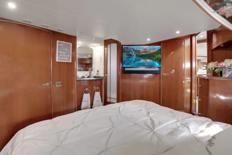 Slide: The Image of Luxurious 2005 Carver 560 Voyager yacht bedroom with TV, wood paneling, and elegant decor. - 62