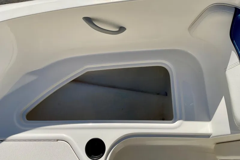 Slide: The Image of 2016 Bayliner Element boat storage compartment, open and empty, with a handle and cup holder. - 10