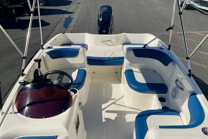 Slide: The Image of 2016 Bayliner Element boat interior with blue and white seating, steering wheel, and canopy frame. - 12