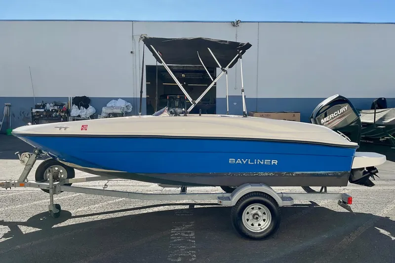 Slide: The Image of 2016 Bayliner Element boat on trailer, blue hull, parked outdoors. - 2