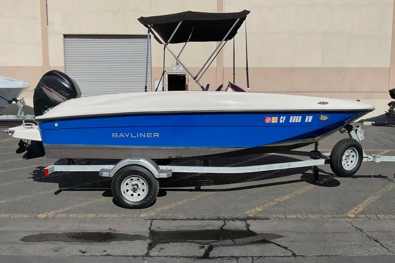 Slide: The Image of 2016 Bayliner Element boat on trailer, blue and white, parked outdoors. - 7