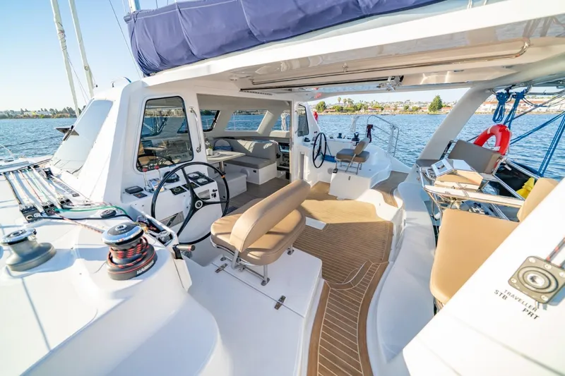 Slide: The Image of 2023 Seawind 1160 Lite catamaran interior with modern helm and seating, docked on calm water. - 10
