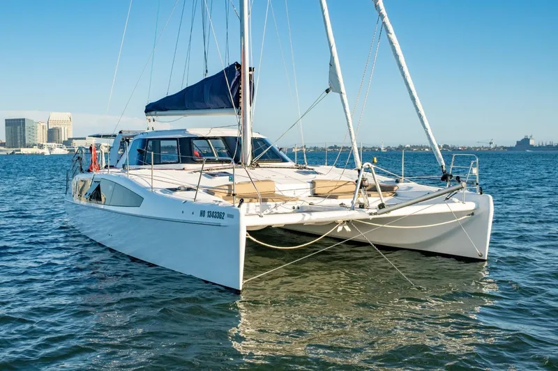 Slide: The Image of 2023 Seawind 1160 Lite catamaran sailing on calm waters near a city skyline. - 4