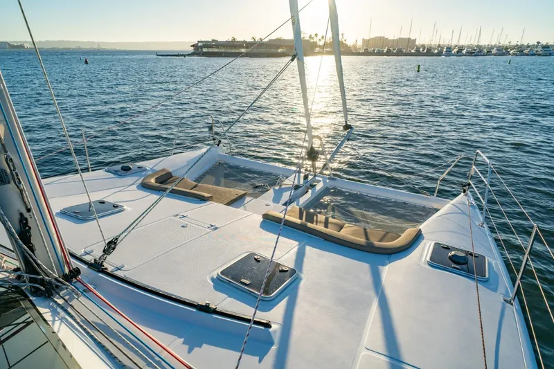 Slide: The Image of 2023 Seawind 1160 Lite catamaran on calm water at sunset, showcasing spacious deck. - 6