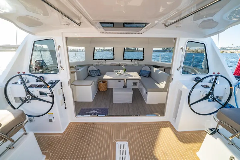 Slide: The Image of 2023 Seawind 1160 Lite catamaran interior with dual steering wheels and spacious seating area. - 8