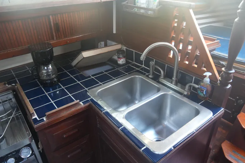 Slide: The Image of 1979 Endeavour 37 yacht kitchen with double sink, blue tile countertop, and coffee maker. - 17