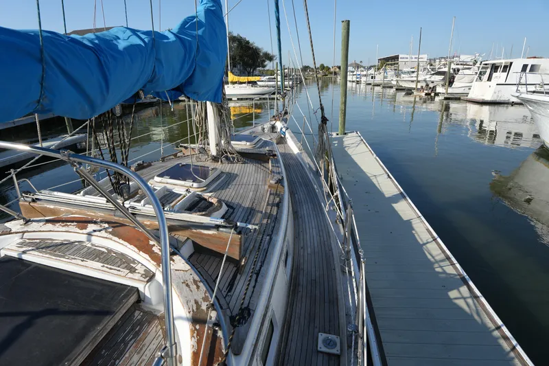 Slide: The Image of 1979 Endeavour 37 sailboat docked at marina, featuring weathered deck and blue sail cover. - 4
