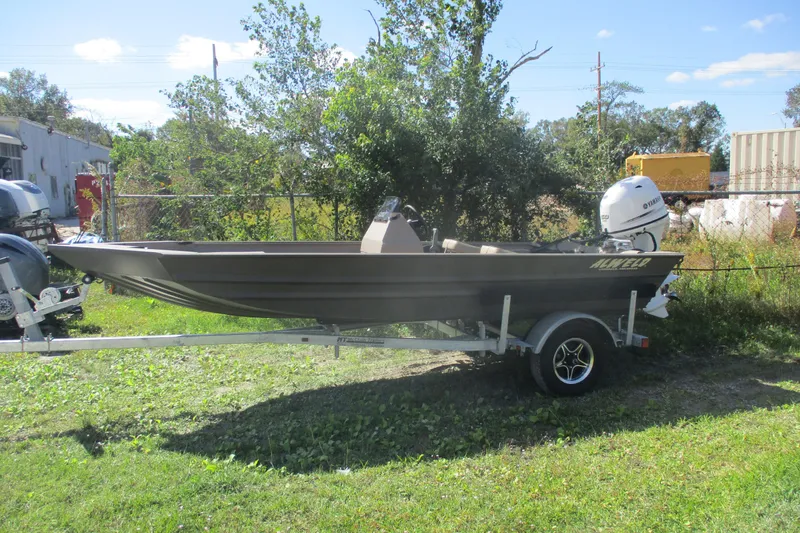 The Image of 2025 Alweld 1652 Marsh boat on trailer, outdoors with Yamaha outboard motor. - 0