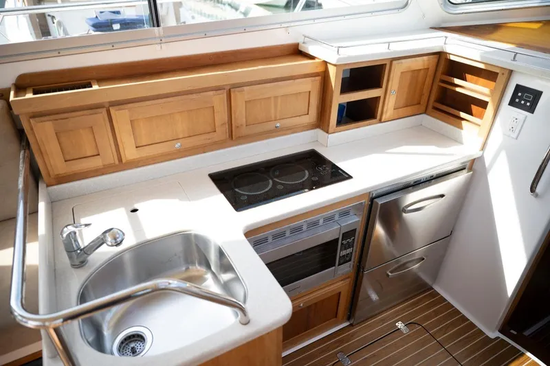 Slide: The Image of 2014 Back Cove 37 yacht kitchen with wooden cabinets, stainless steel sink, and modern appliances. - 19