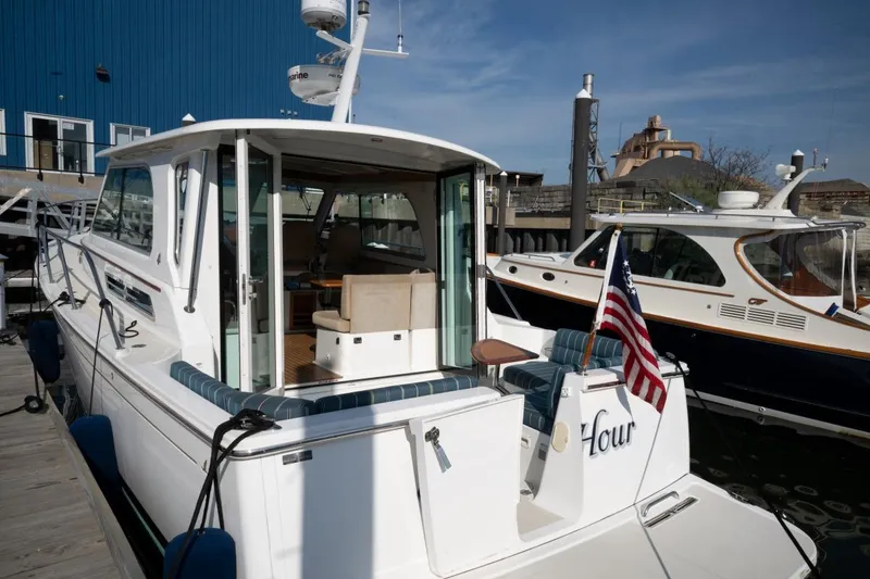 Slide: The Image of 2014 Back Cove 37 yacht docked, featuring a spacious deck and American flag. - 25