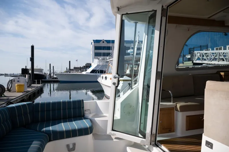 Slide: The Image of 2014 Back Cove 37 yacht interior with marina view, featuring striped seating and open cabin door. - 26