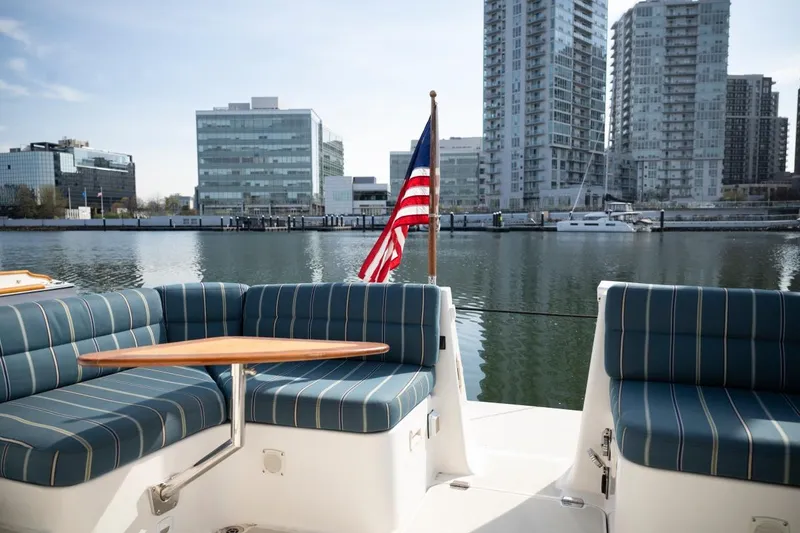 Slide: The Image of 2014 Back Cove 37 yacht with striped seating, docked near modern cityscape. - 29