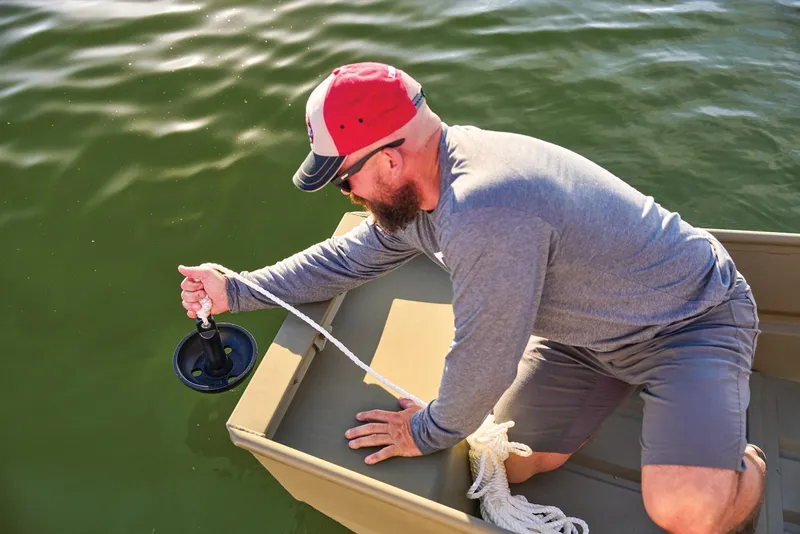 Slide: The Image of Manufacturer Provided Image: Man in a boat using a rope anchor on water, wearing a red cap and sunglasses. - 51